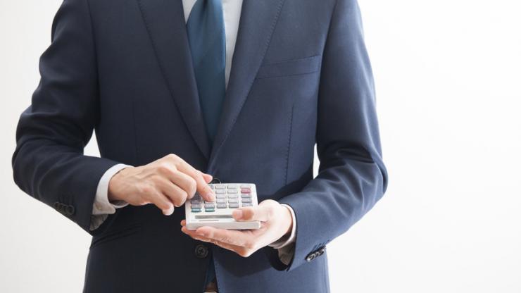 Homme en costume tenant une calculatrice