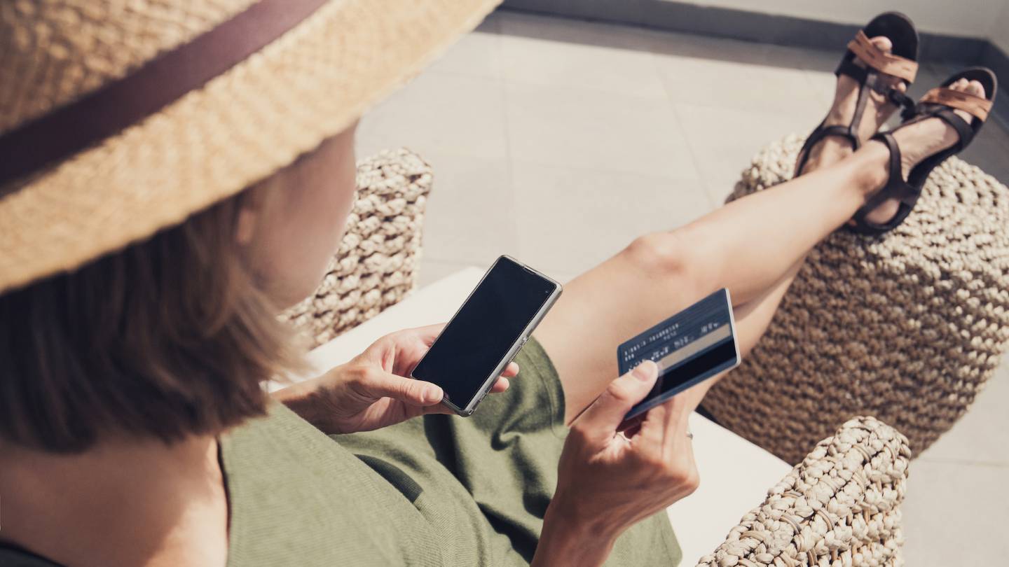 Jeune femme en vacances utilisant sa carte bancaire et son mobile
