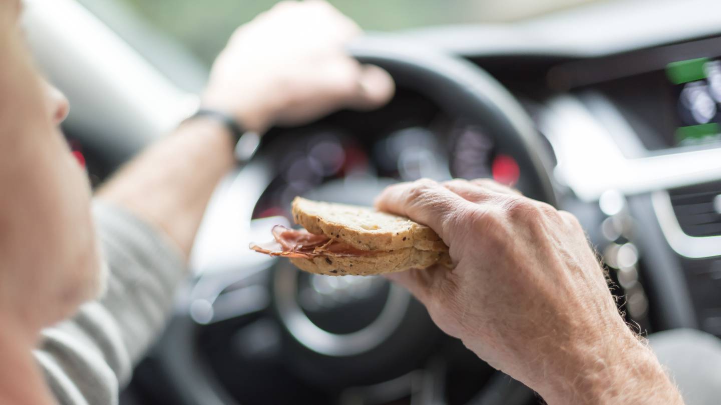 Un conducteur mange un sandwich au volant