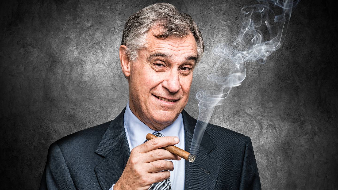 Un homme d'affaire souriant fume un cigare
