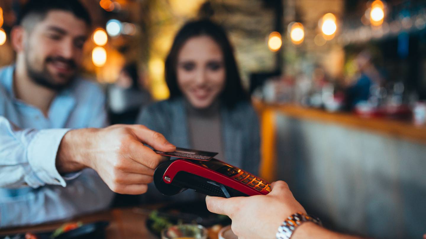 Un couple au restaurant paie sans contact par carte bancaire