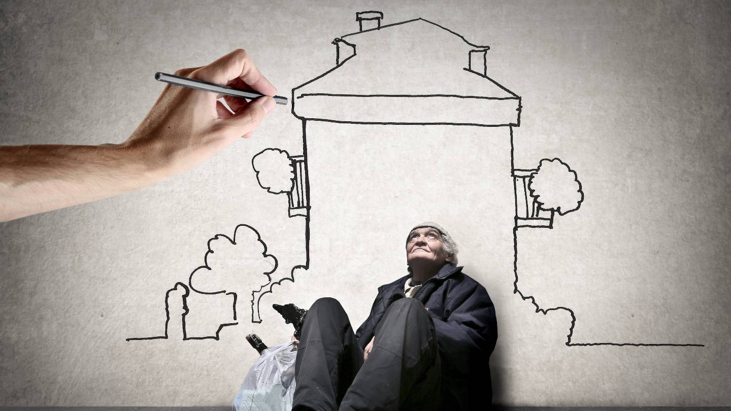 Une main dessine un logement au-dessus d'un sans-abri