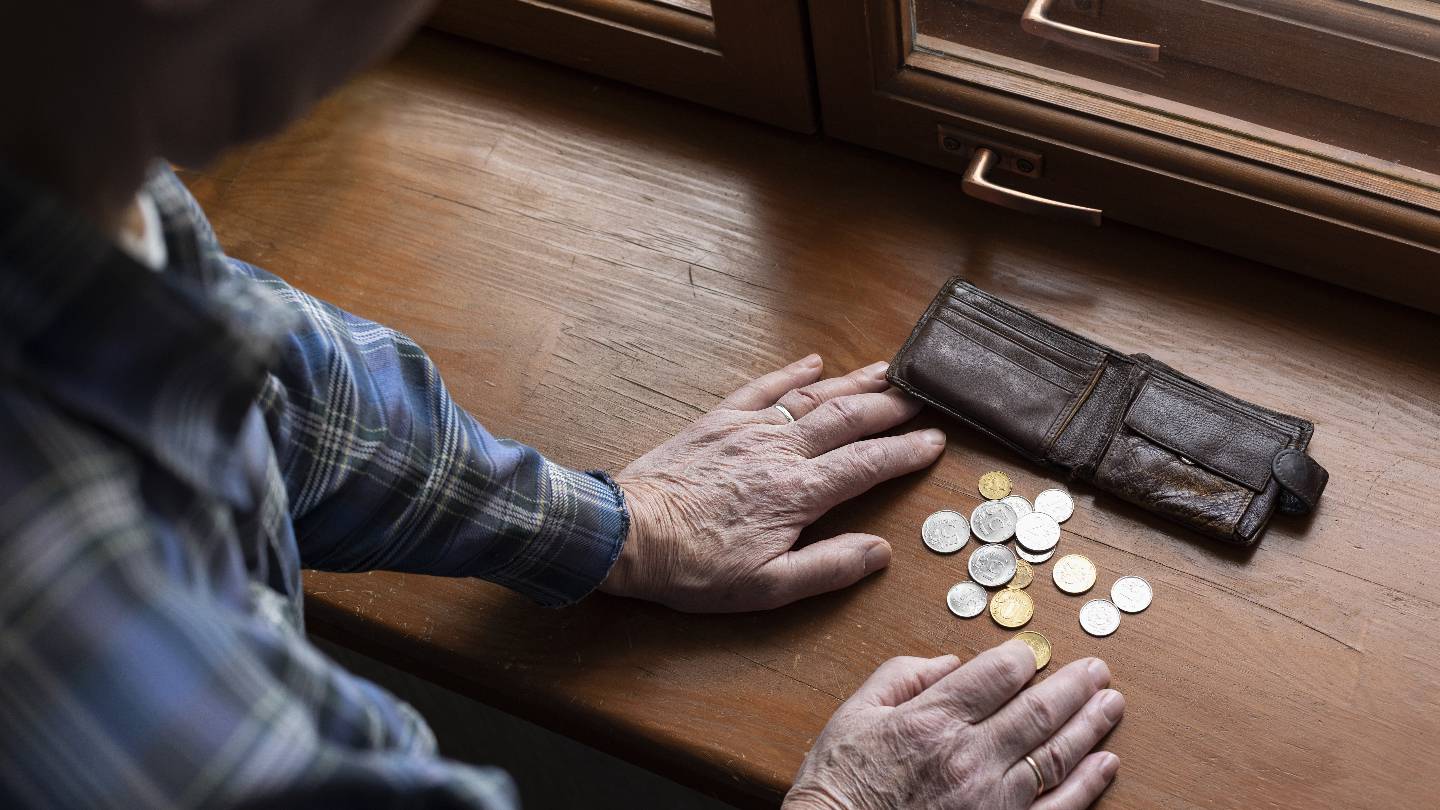 Un vieil homme cote les pices de son porte-monnaie