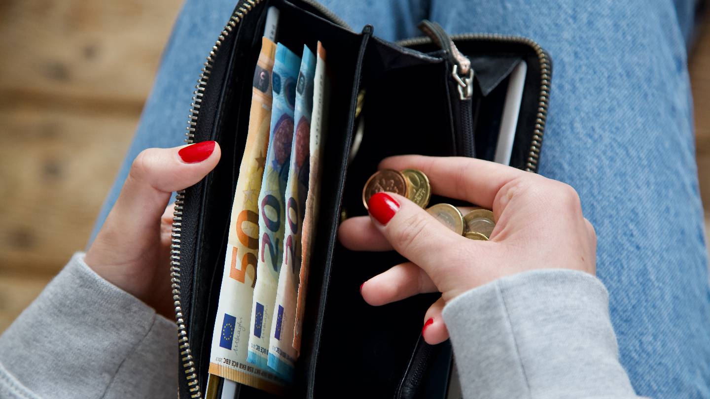 Une jeune femme compte son argent dans son porte-monnaie