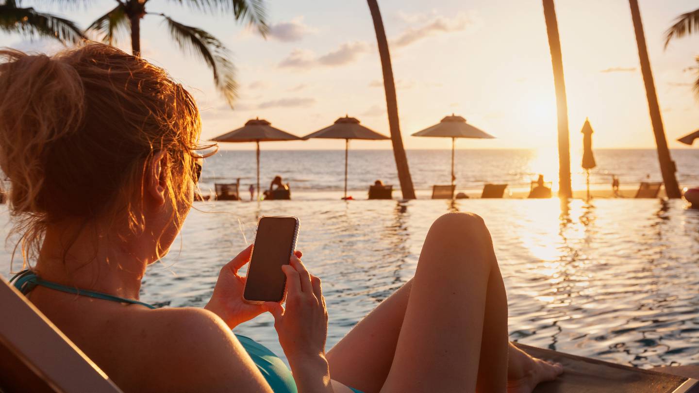 Une femme utilise son smartphone sur une plage