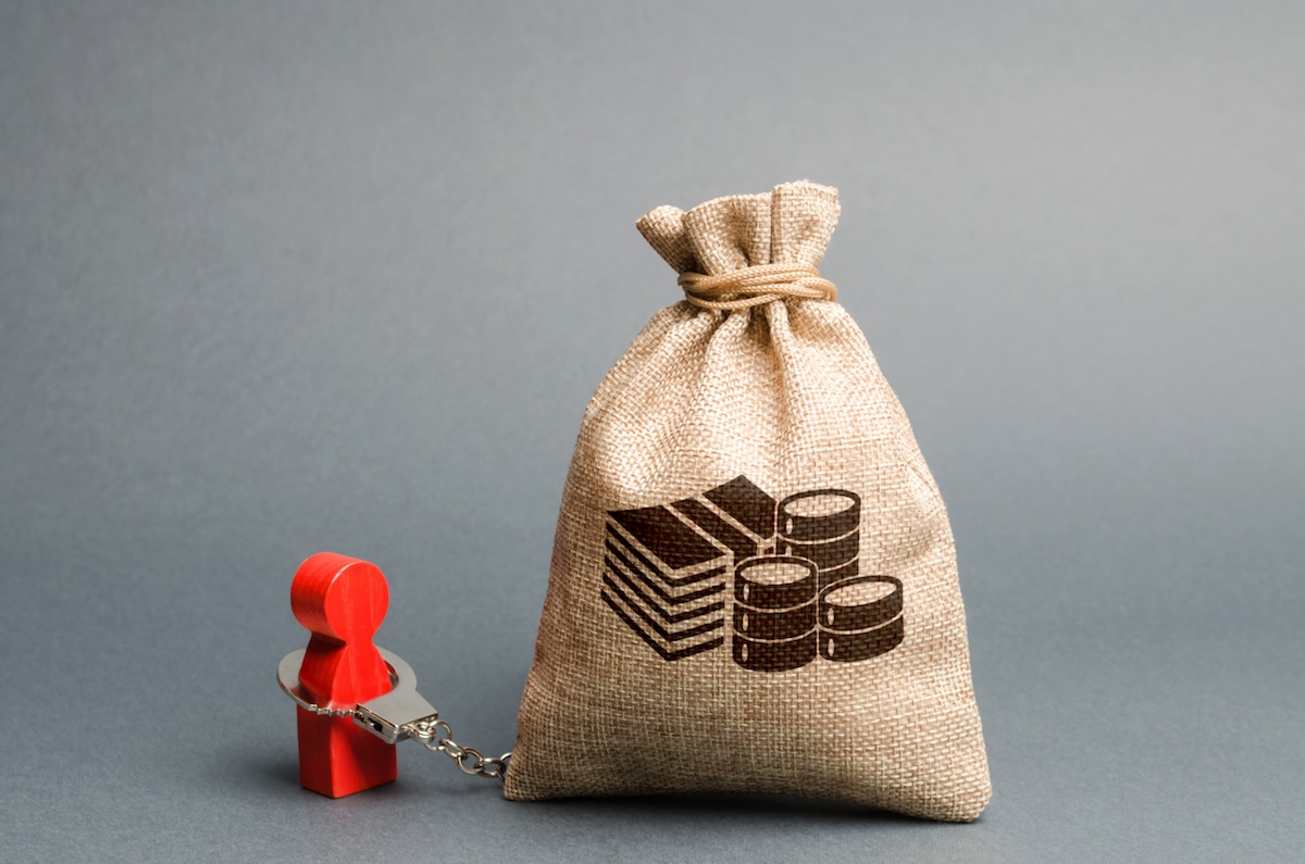 Un sac d'argent et une figurine menotte, symboles d'un surendettement ou d'un incident de paiement.