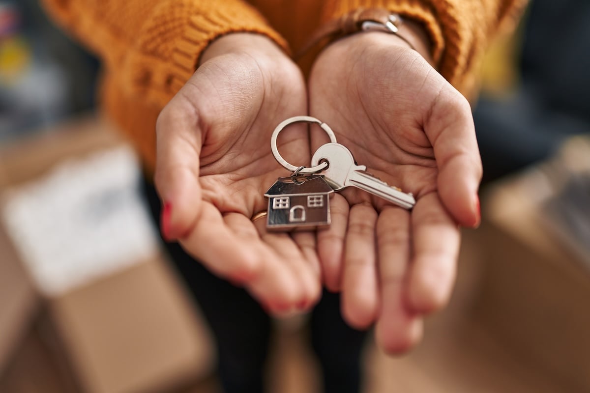 Quelqu'un tient dans ses mains un porte-clef en forme de maison.