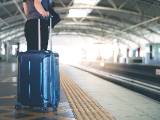 Quelqu'un tient une valise dans une gare.