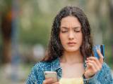 Une femme regarde sa carte bancaire et son tlphone.