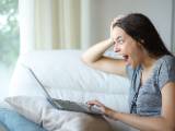 Une femme regarde son ordinateur l'air surpris