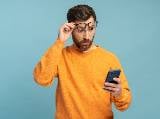 Un homme regarde son tlphone l'air surpris.