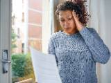 Une femme regarde un document en se tenant la tte.