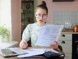 Une femme regarde son ordinateur et des documents l'air surpris.