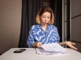 Une femme regarde un document l'air surpris.