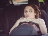 Une jeune femme au volant d'une voiture.