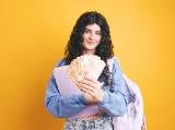 Une femme avec un sac  dos tient plusieurs billets de 50 euros.